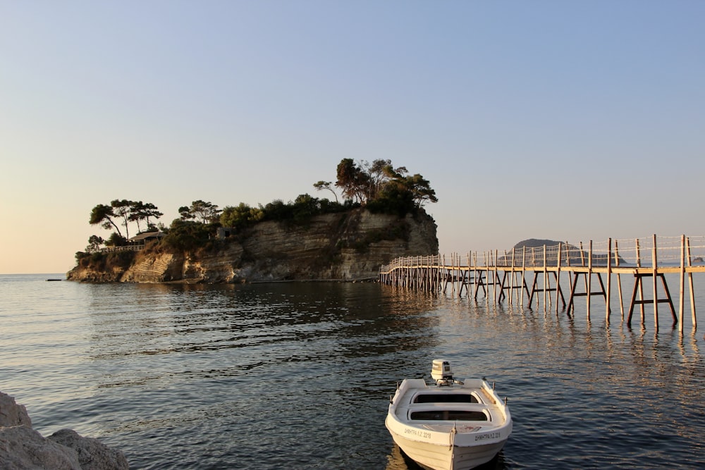 white and blue boat on sea near brown rock formation during daytime