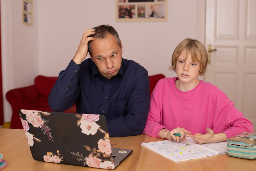 man in blue dress shirt sitting beside girl in pink long sleeve shirt