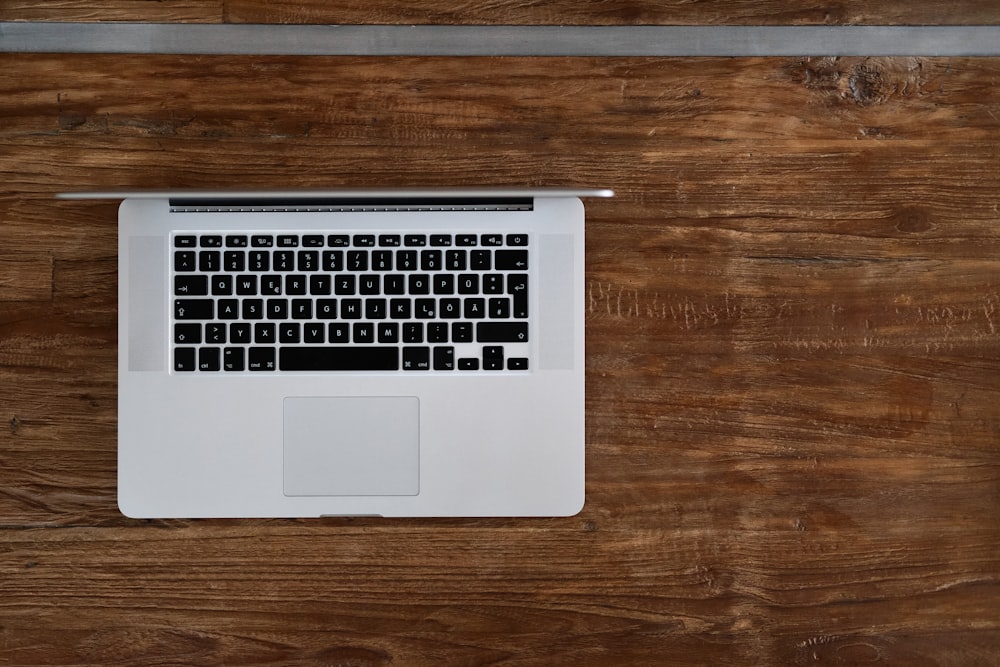 macbook pro na mesa de madeira marrom