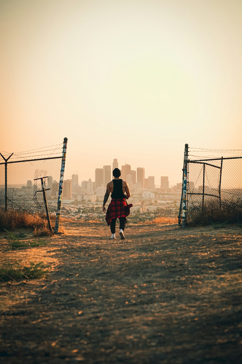 man in red jacket standing beside fence during daytime