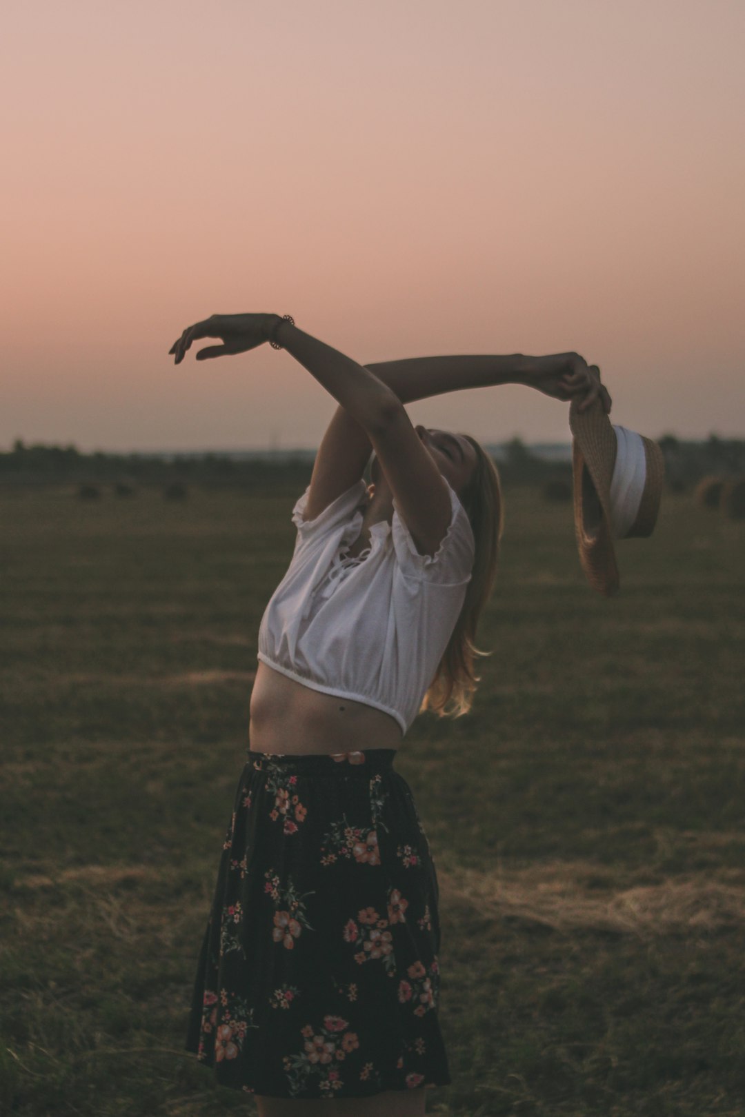 woman in white tank top and black floral skirt raising her hands