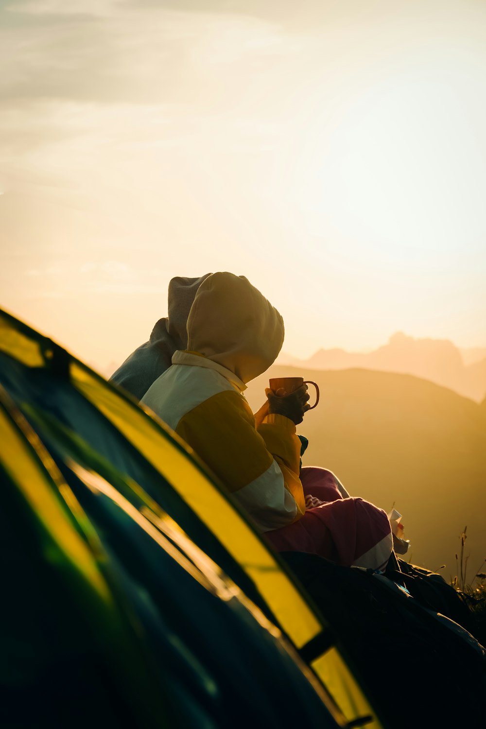 Mann und Frau sitzen bei Sonnenuntergang auf gelbem und schwarzem Auto