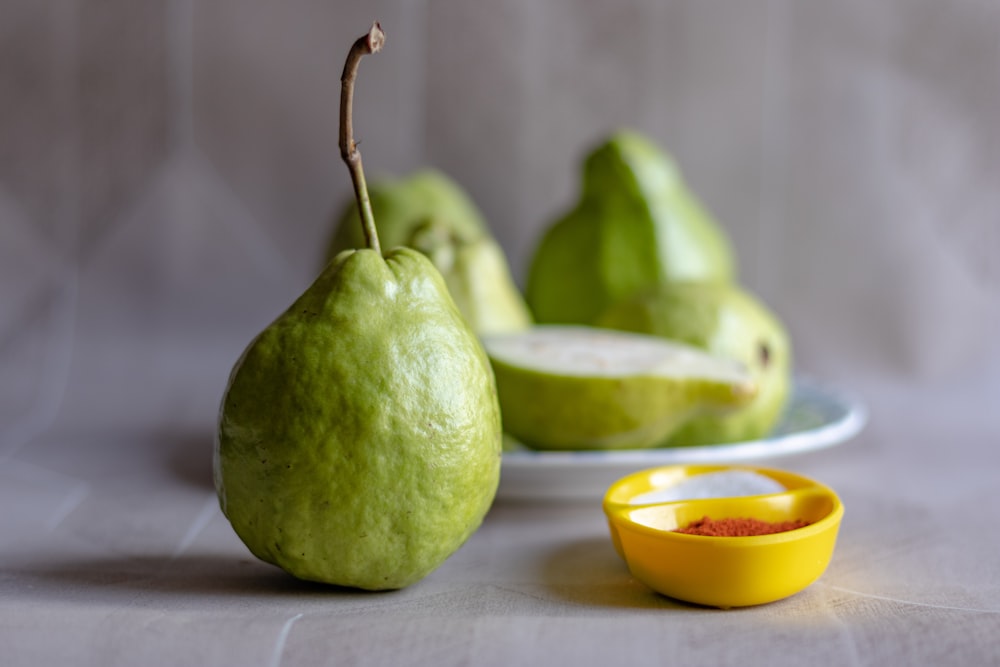 2 green round fruits on white table