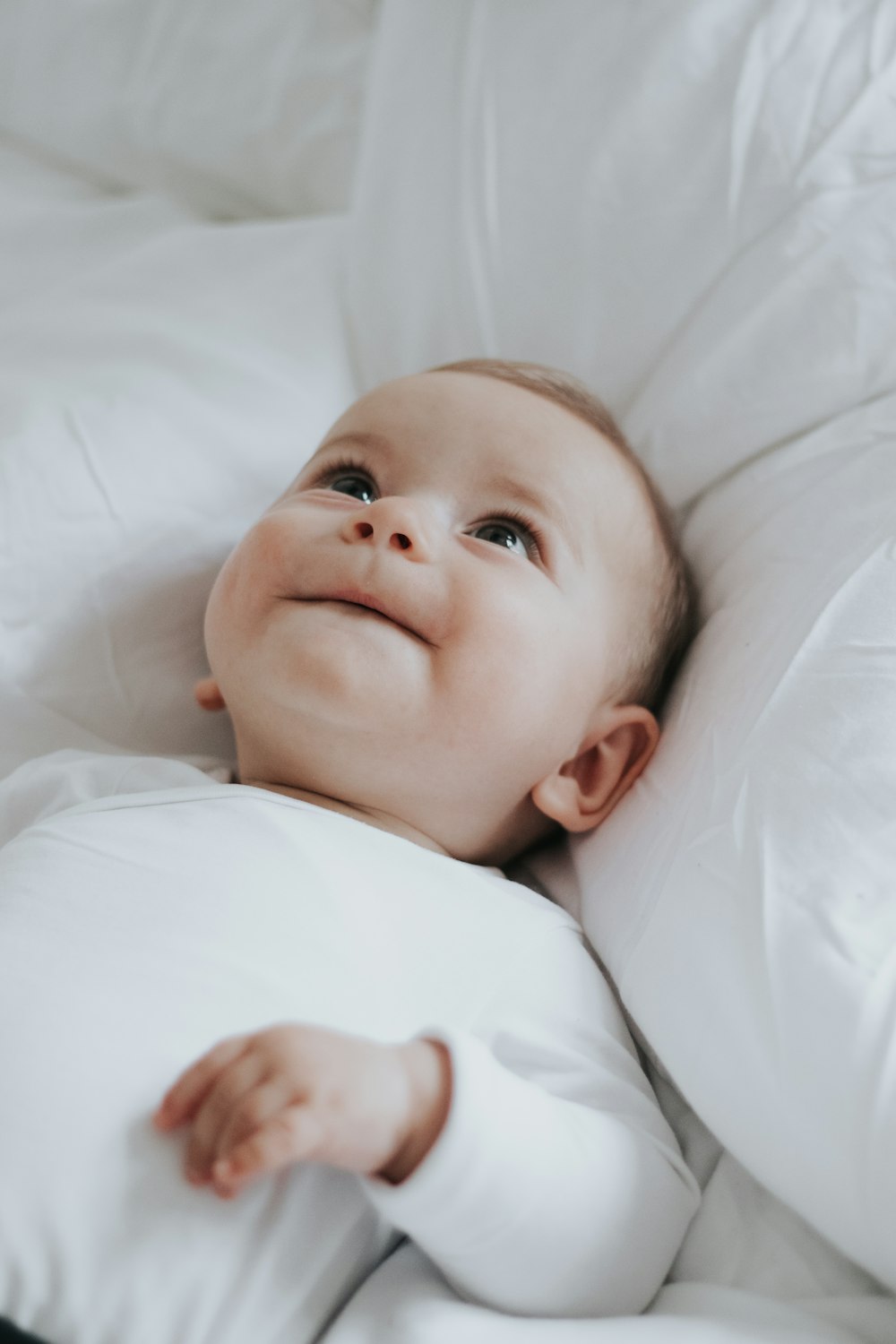 um bebê deitado em uma cama com lençóis brancos