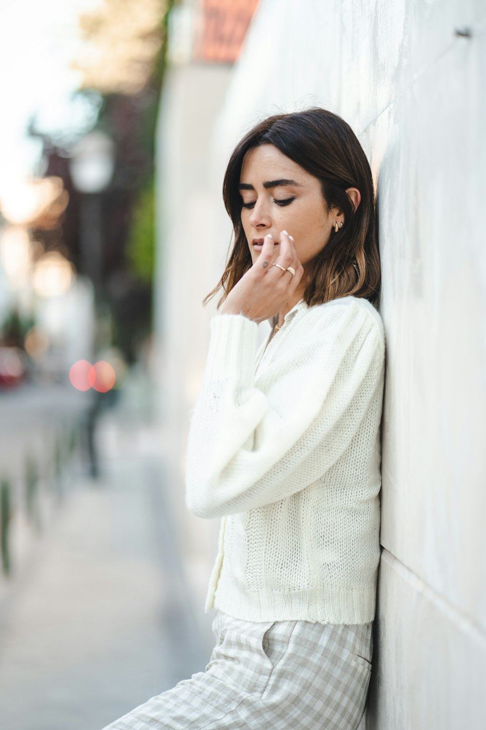 woman in white sweater standing beside white wall