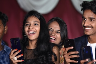 A relaxed group of people laughing together over their phones, sharing memes in a cozy, inviting space.