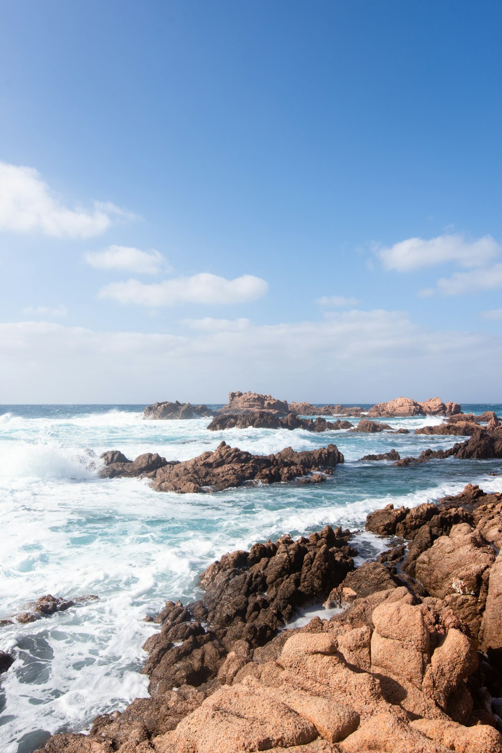 brown rock formation on sea under blue sky during daytime