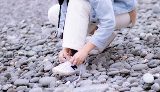 A runner tying their shoes next to a scenic Mediterranean coastline.