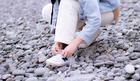 A runner tying their shoes next to a scenic Mediterranean coastline.
