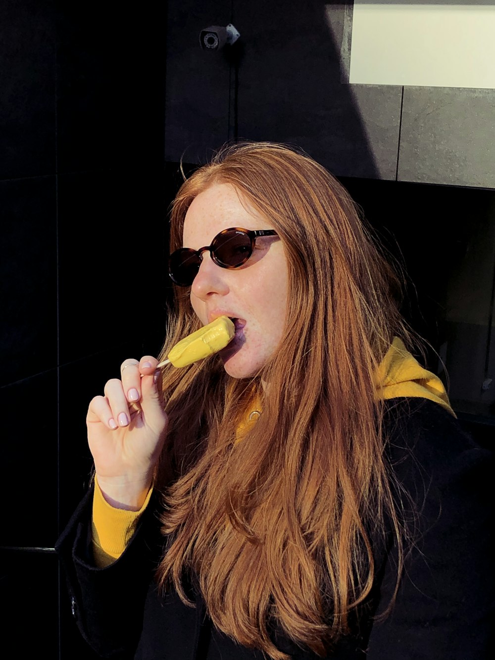 woman in black and yellow jacket wearing black sunglasses