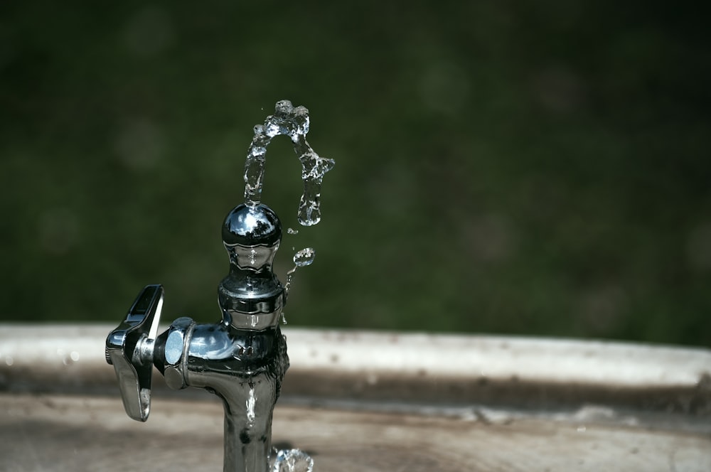 Silberner Wasserhahn mit Wassertröpfchen