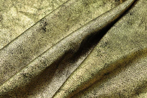 A close-up of a finely woven material roll showcasing rich textures in black and gold hues.
