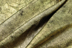 A detailed capture of a black and gold patterned fabric draped gracefully over a minimalist surface.