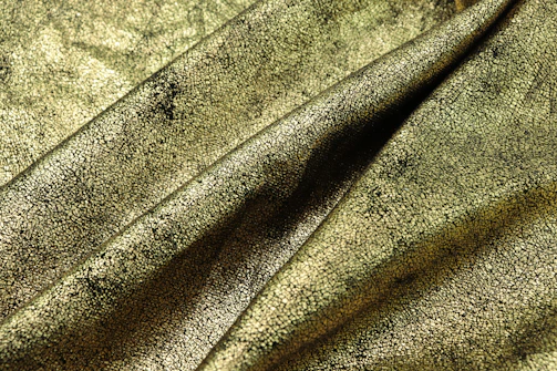 Close-up of luxurious golden yarn strands artfully arranged on a black background.