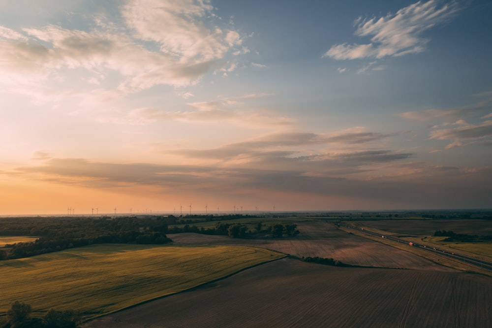 brown field under white clouds during daytime