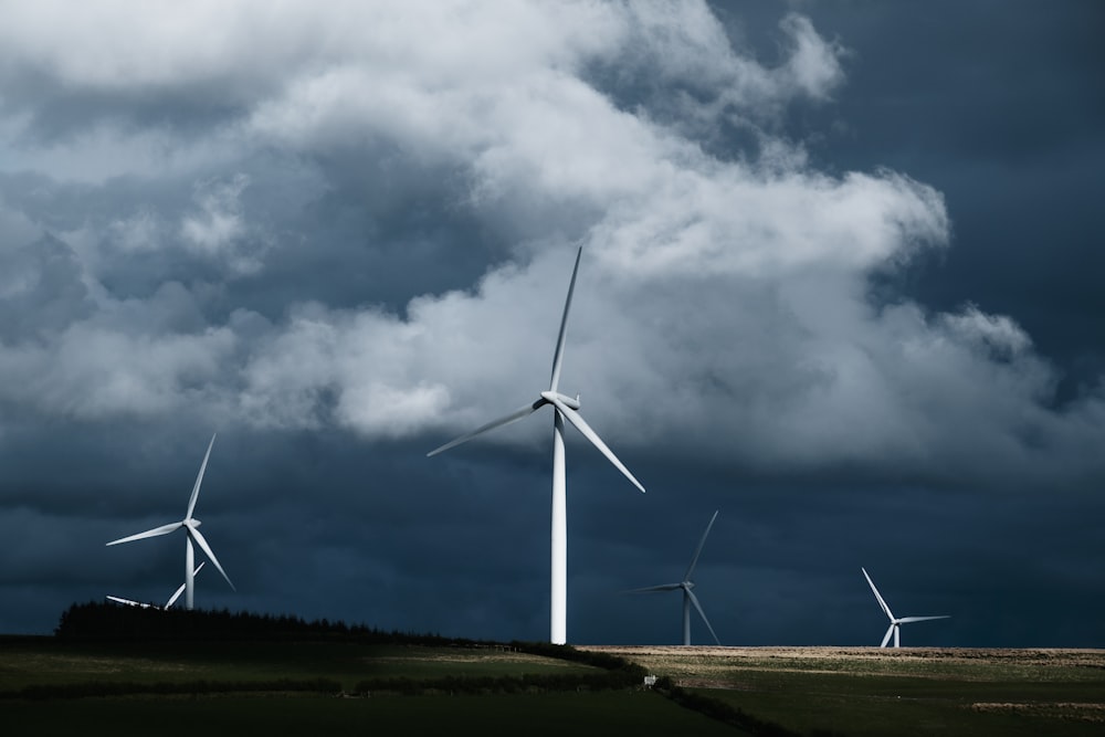 white wind turbines on green grass field under gray clouds