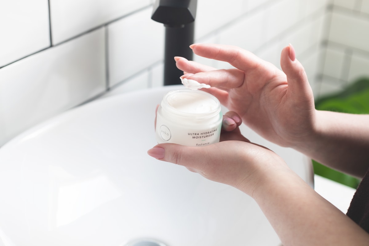 A person applying face cream at a bathroom sink