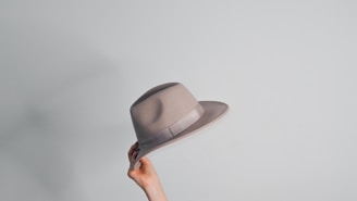 a woman's hand holding a gray hat