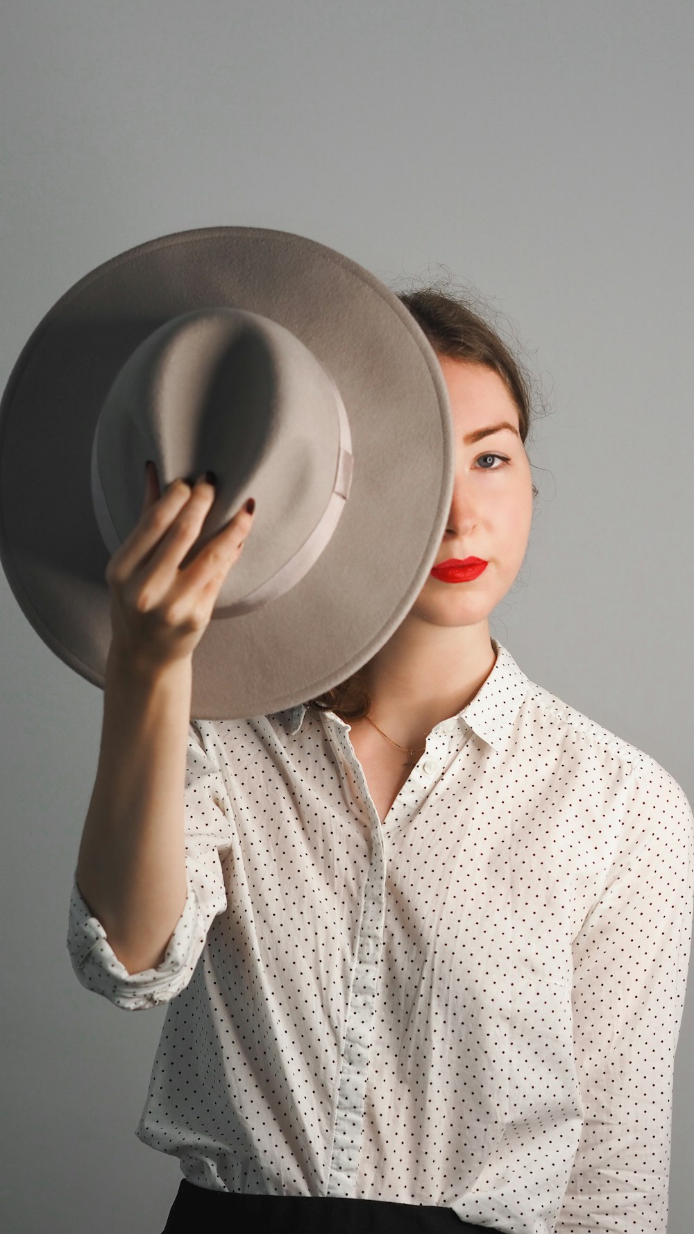 woman in white and gray long sleeve shirt holding black hat