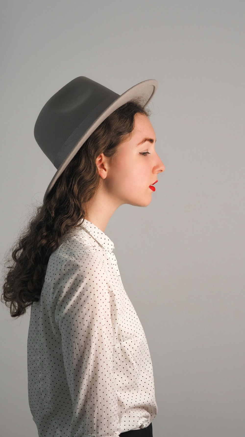 woman in white and black polka dot shirt wearing black hat