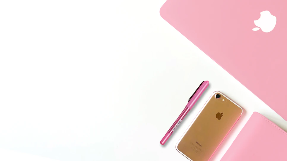 A softly lit photo of a student smiling with a notebook and laptop, surrounded by blush pink and gold accents.