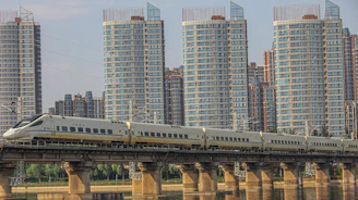 High-speed trains crossing a sleek, futuristic bridge over water.