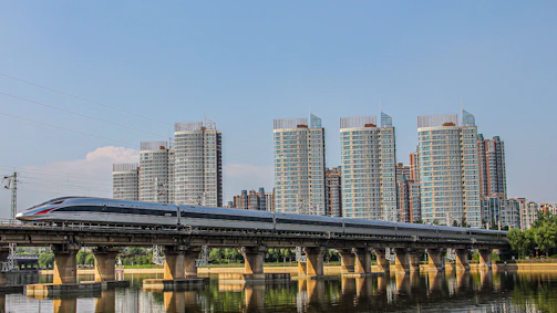 A panoramic view of a modern high-speed train crossing a bridge between France and Morocco at sunset.