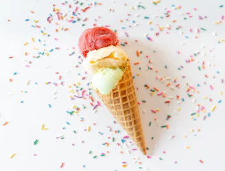 A colorful scoop of ice cream in a waffle cone with sprinkles.
