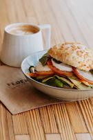 Close-up of a colorful panino filled with fresh ingredients, resting on a rustic wooden table.