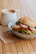 Close-up of a freshly made sandwich and a hot coffee cup with the Brewvista logo on a wooden table.