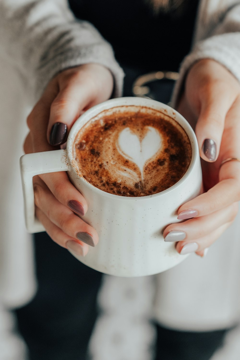 personne tenant une tasse en céramique blanche avec un liquide brun