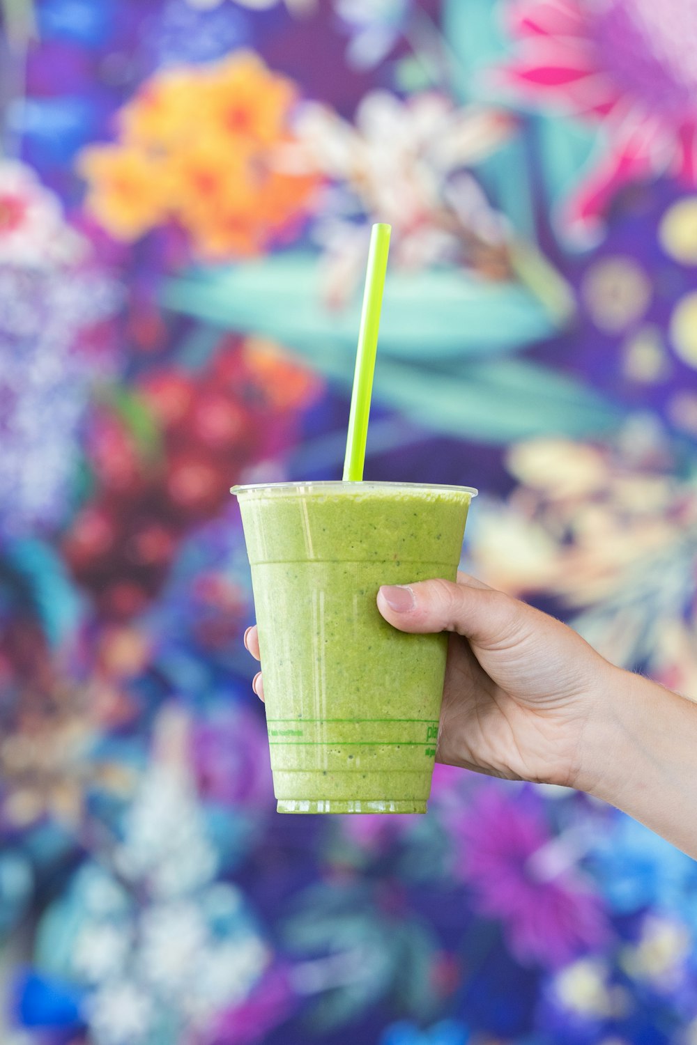 person holding green plastic cup with green straw