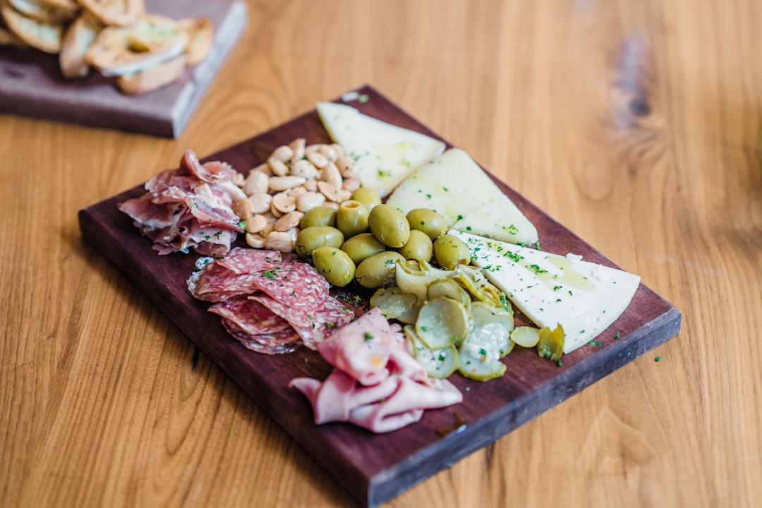 sliced meat with green vegetable on brown wooden chopping board