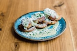 A plate of delicious fried food garnished with grated cheese and chopped herbs on a rustic wooden table. The dish appears to be served with a creamy sauce, adding a gourmet touch to the presentation.