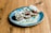 A plate of delicious fried food garnished with grated cheese and chopped herbs on a rustic wooden table. The dish appears to be served with a creamy sauce, adding a gourmet touch to the presentation.
