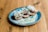 A plate of delicious fried food garnished with grated cheese and chopped herbs on a rustic wooden table. The dish appears to be served with a creamy sauce, adding a gourmet touch to the presentation.