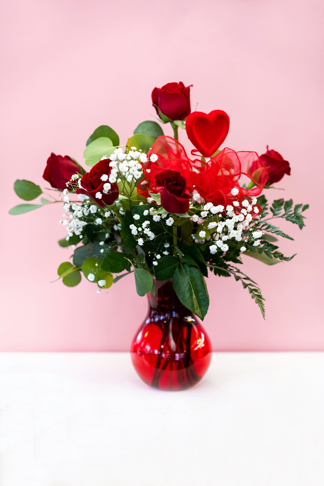 red and white flowers in red glass vase