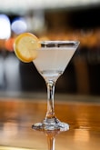 clear cocktail glass with sliced lemon on brown wooden table