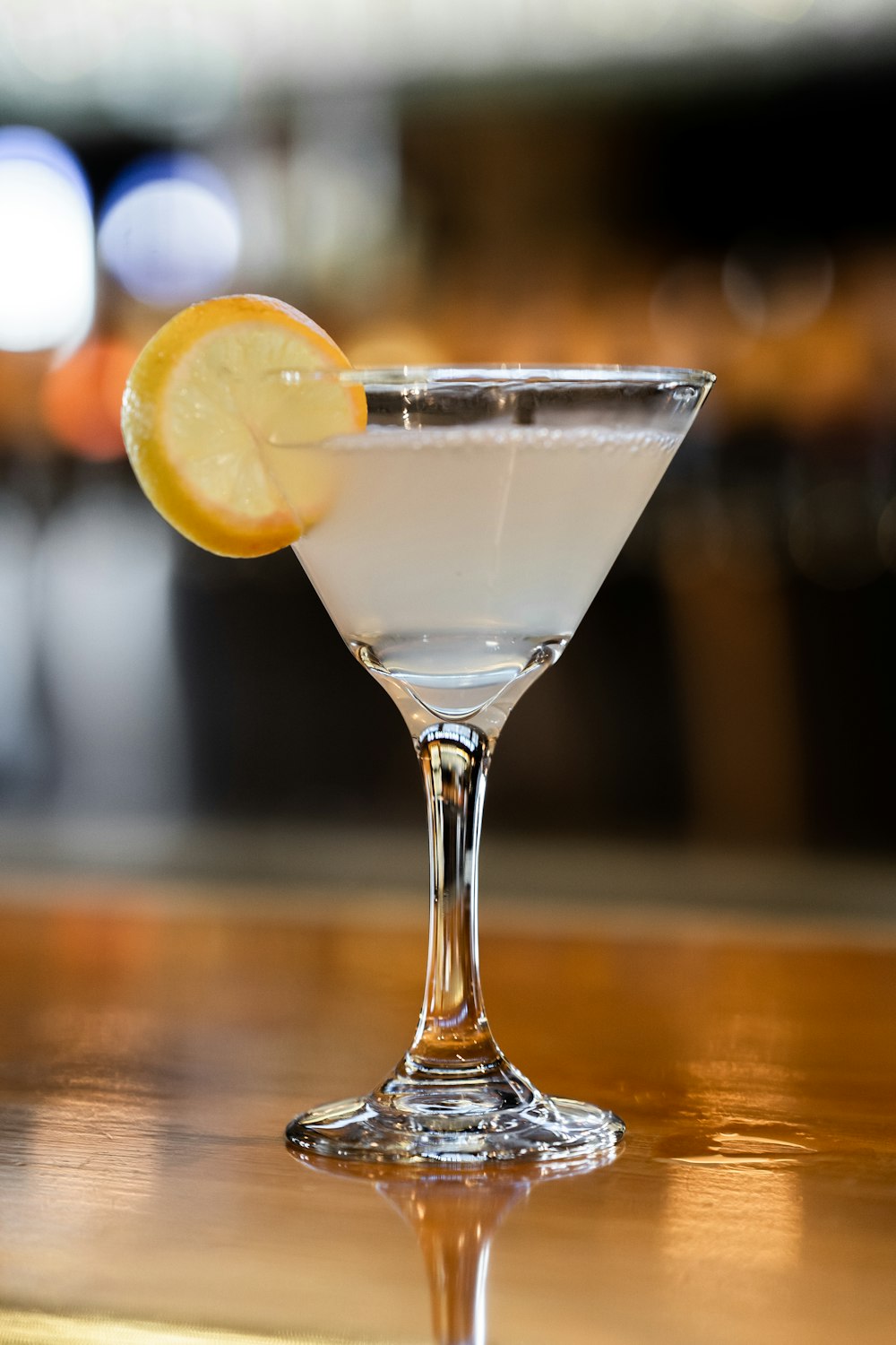 clear cocktail glass with sliced lemon on brown wooden table