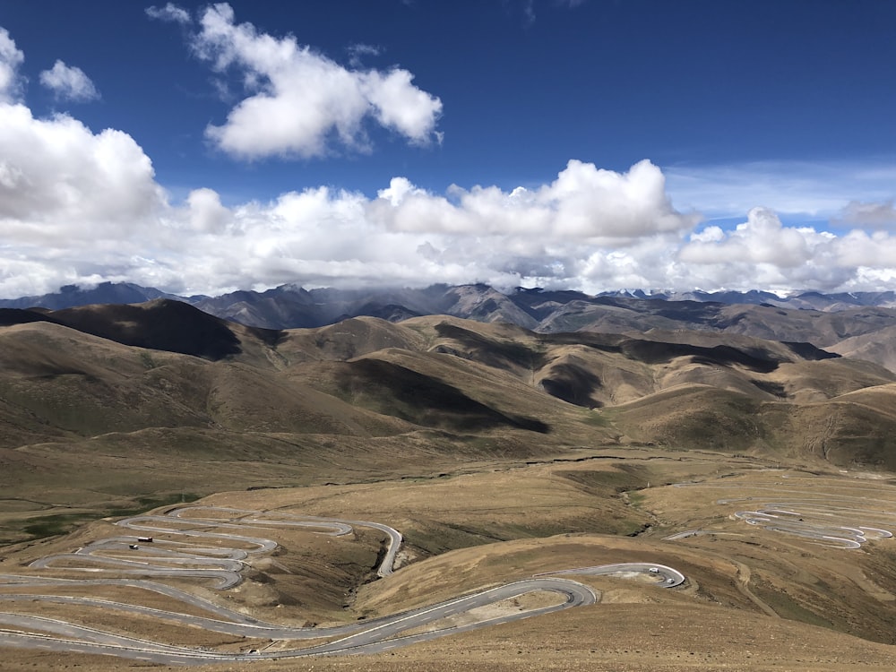 brown and green mountains under blue sky and white clouds during daytime