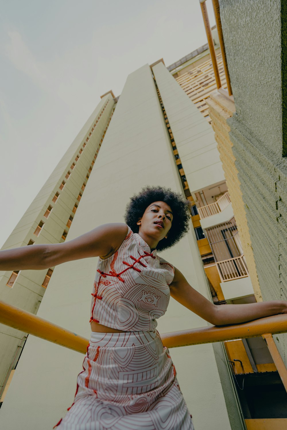 woman in white and red tank top standing on yellow metal bar during daytime