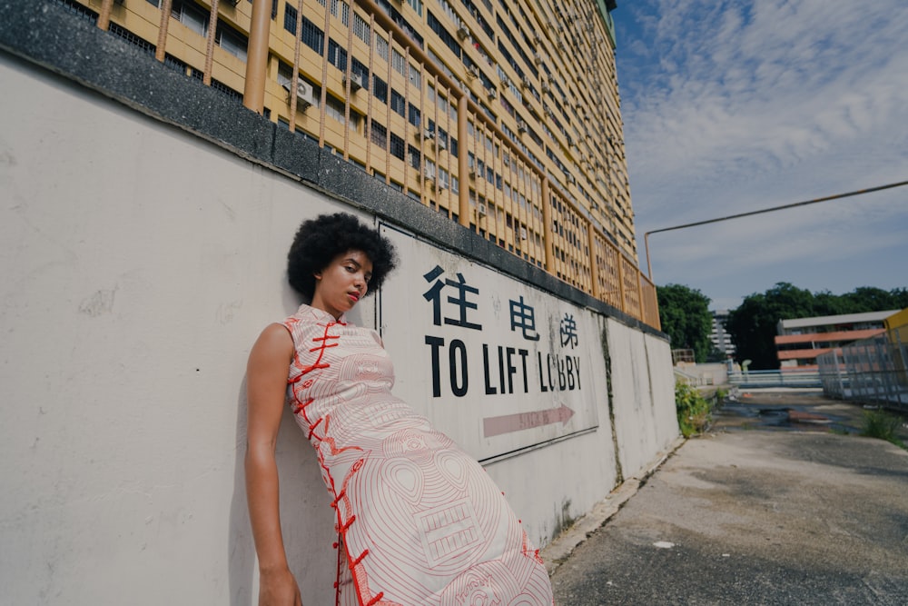 woman in pink and white sleeveless dress standing beside wall with graffiti during daytime