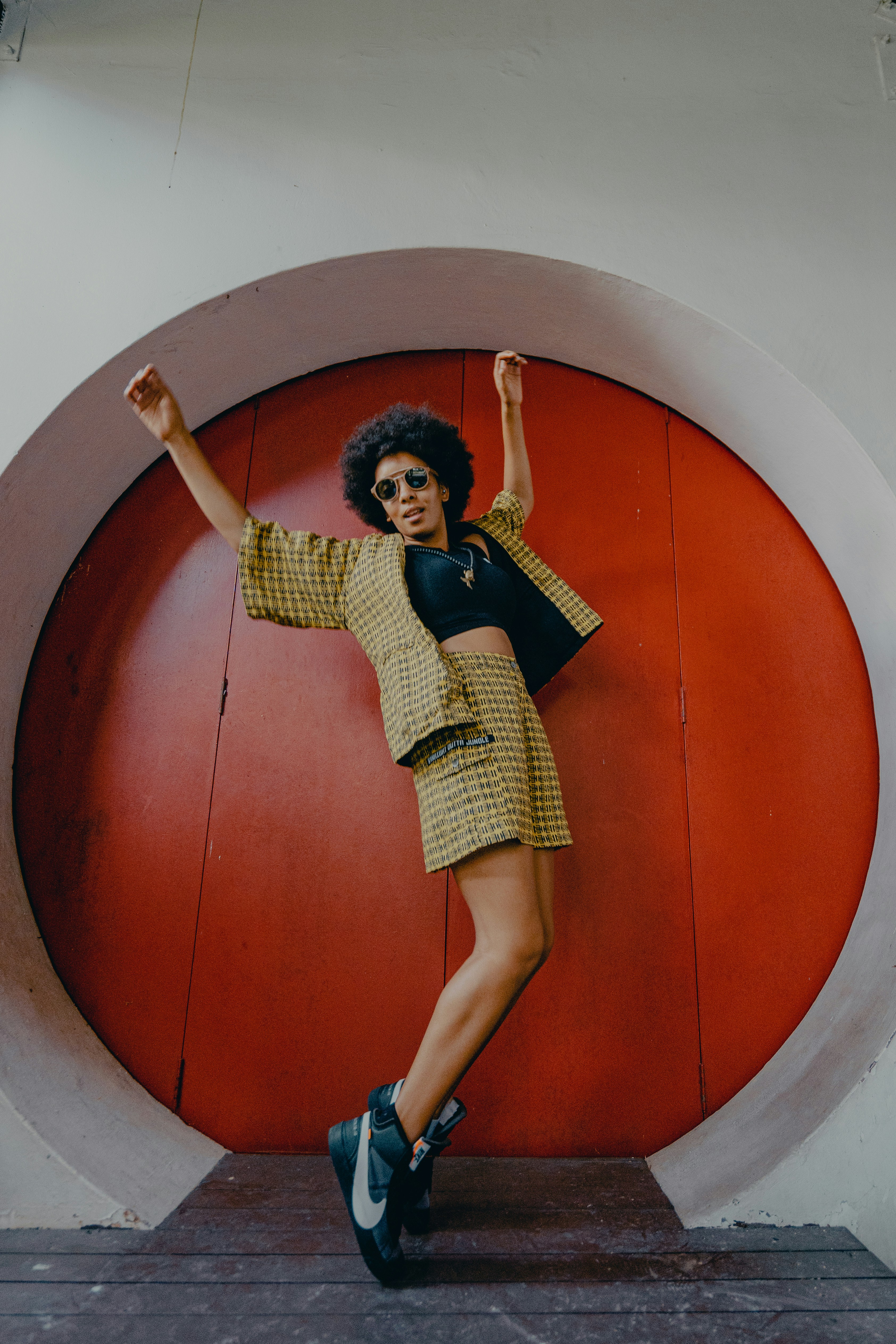 a person posing in front of a round red door