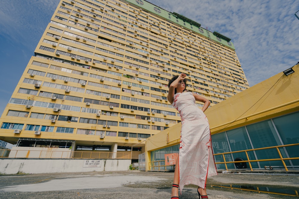 woman in white dress standing near beige concrete building during daytime