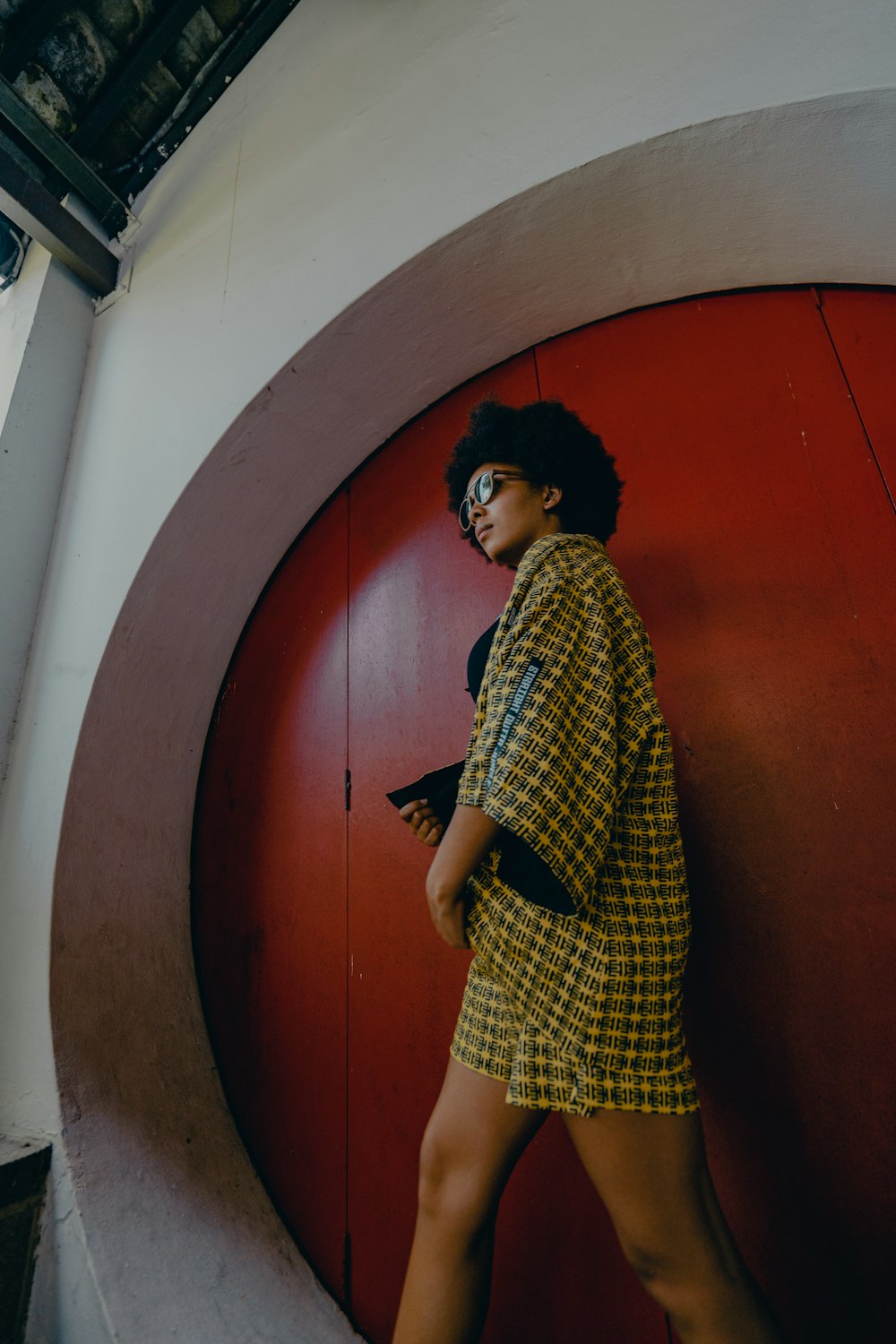 woman in black and white checkered dress standing beside red wooden door