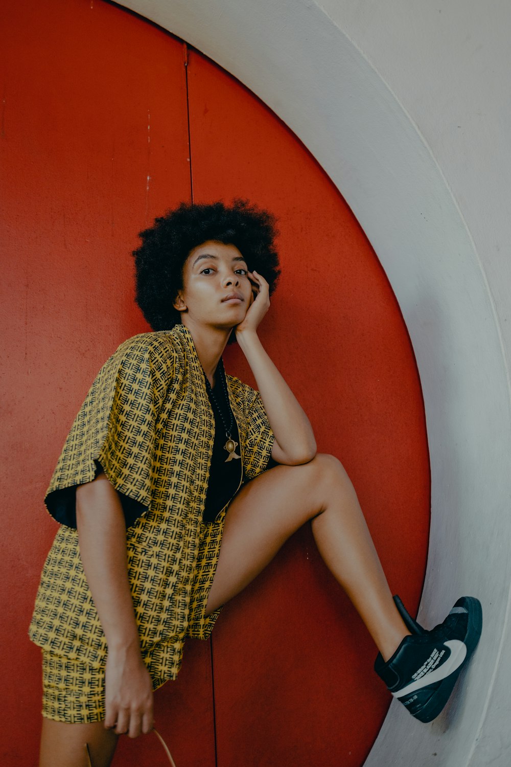 woman in yellow and black dress sitting on red chair