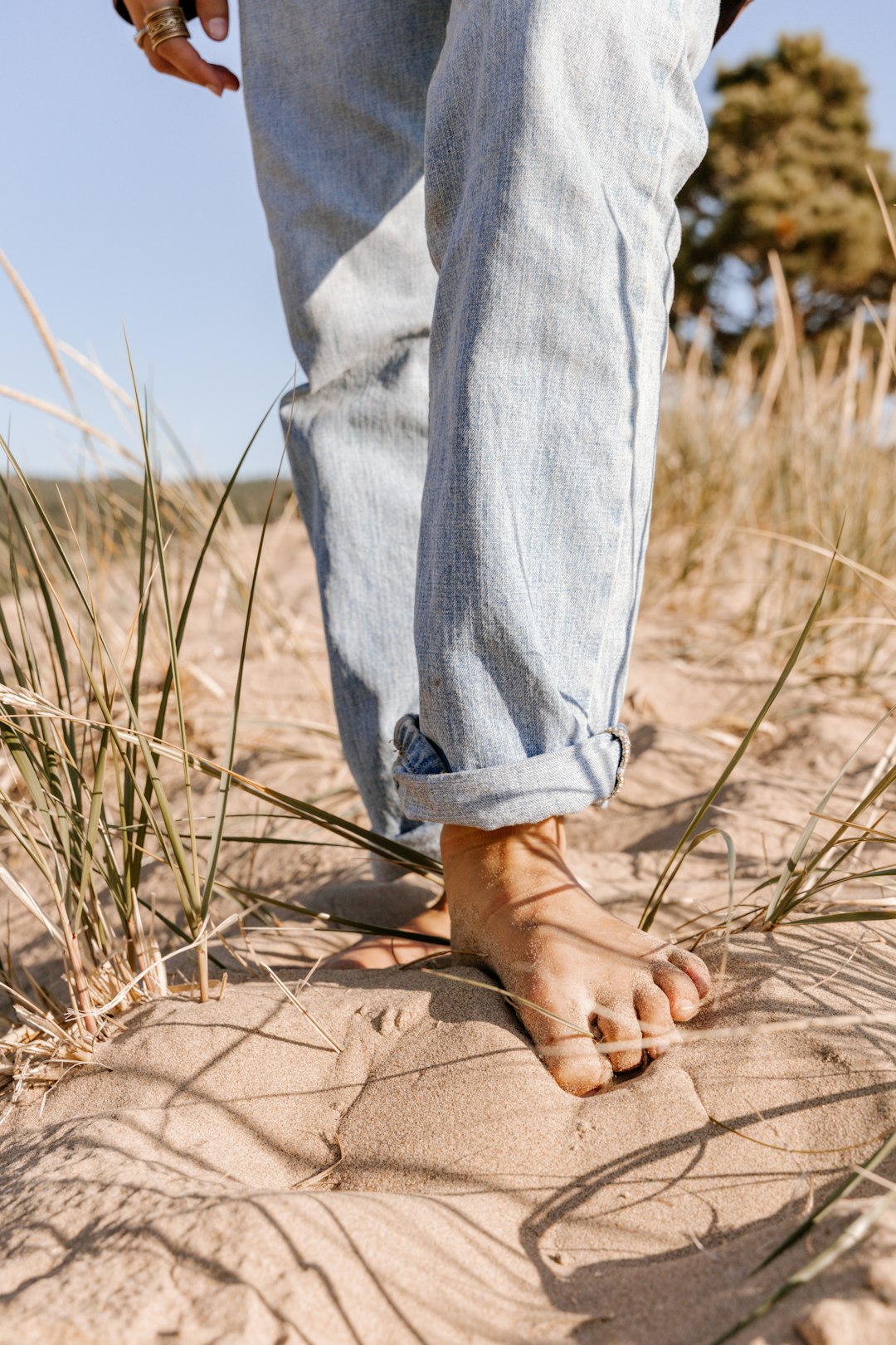person in blue denim jeans standing on brown sand during daytime