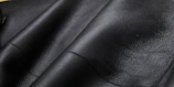 Sleek black microfiber leather samples displayed on a silver metallic surface.