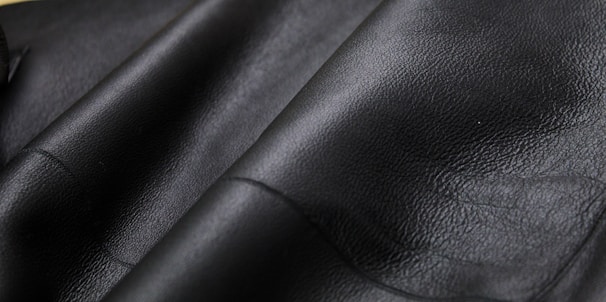 Close-up 8k shot of a dark textured surface resembling premium leather with subtle light reflections.