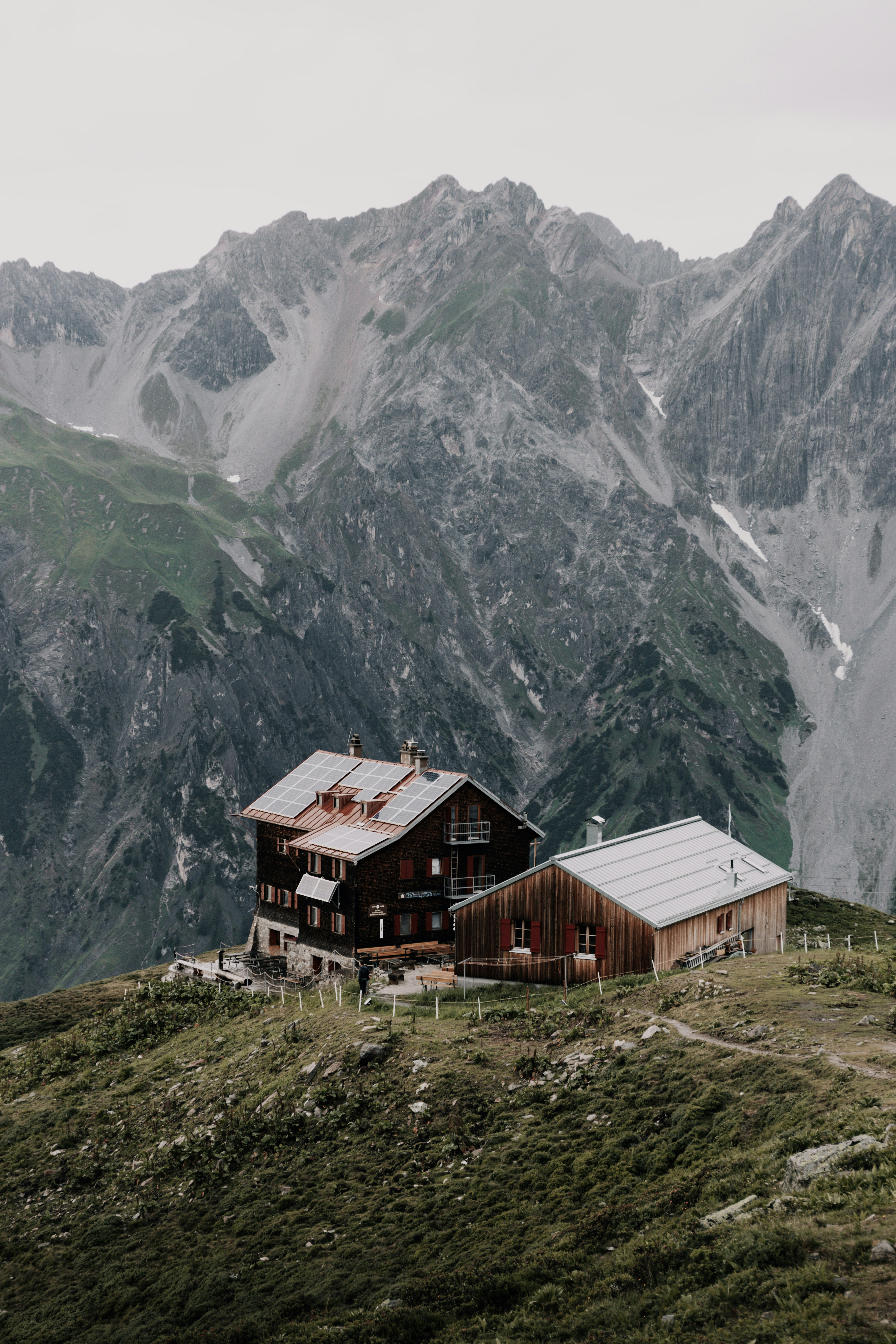 brown wooden house on green grass field near mountain during daytime